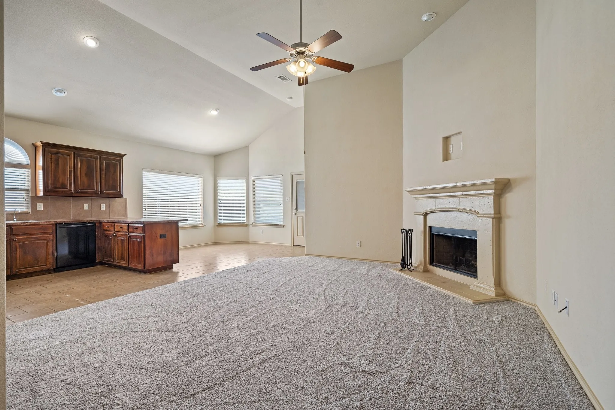 Unfurnished living room with high vaulted ceiling, light carpet, and ceiling fan