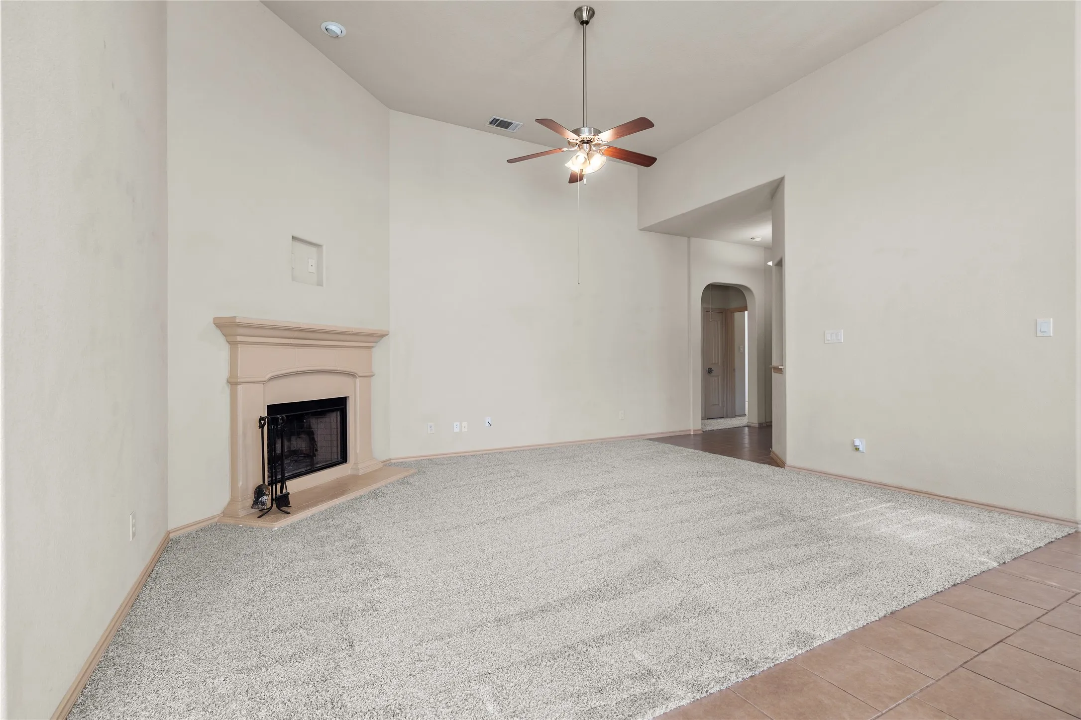 Unfurnished living room with high vaulted ceiling, ceiling fan, and light tile flooring