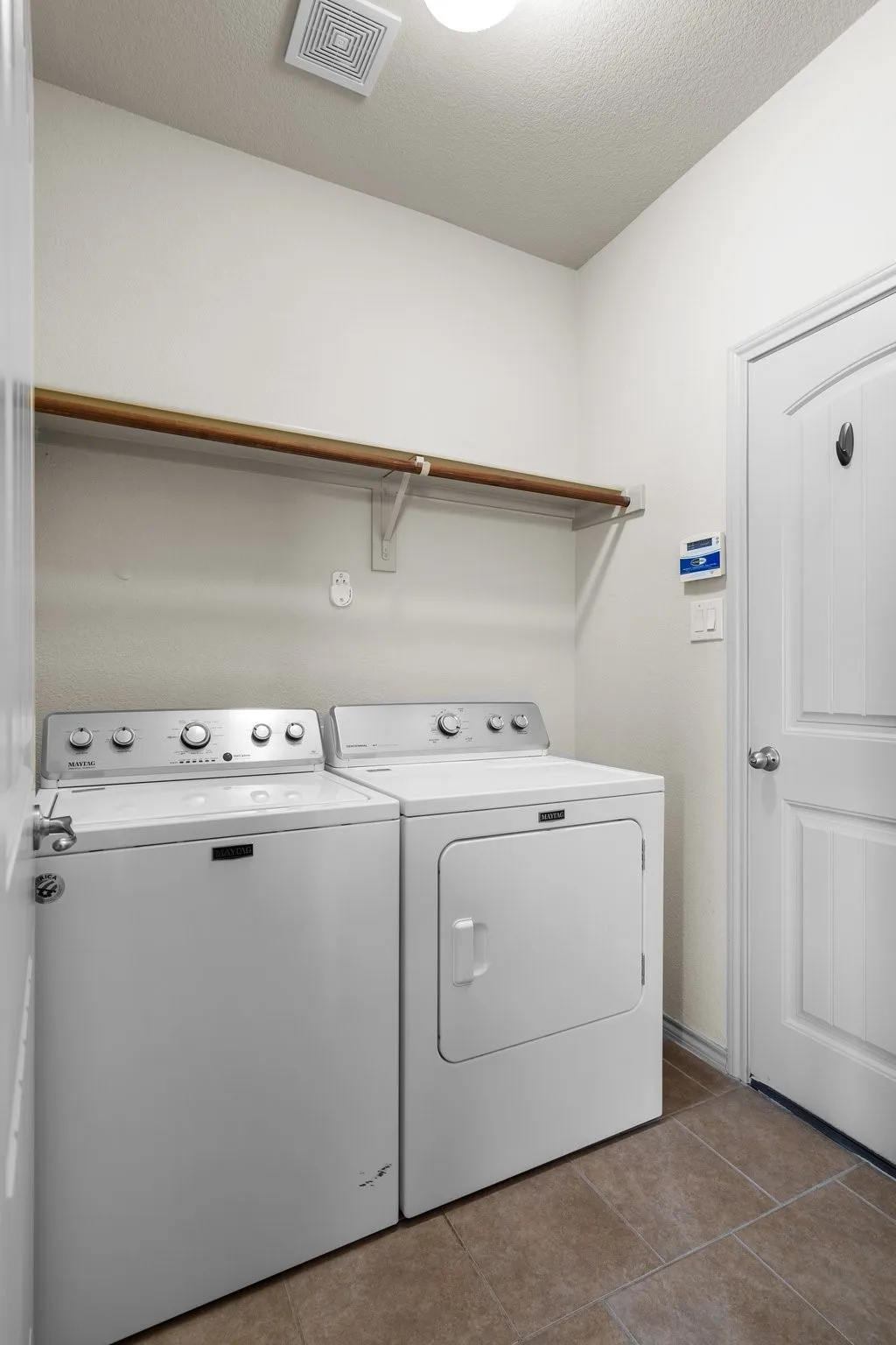 Laundry room featuring washer and clothes dryer, tile flooring, and a textured ceiling