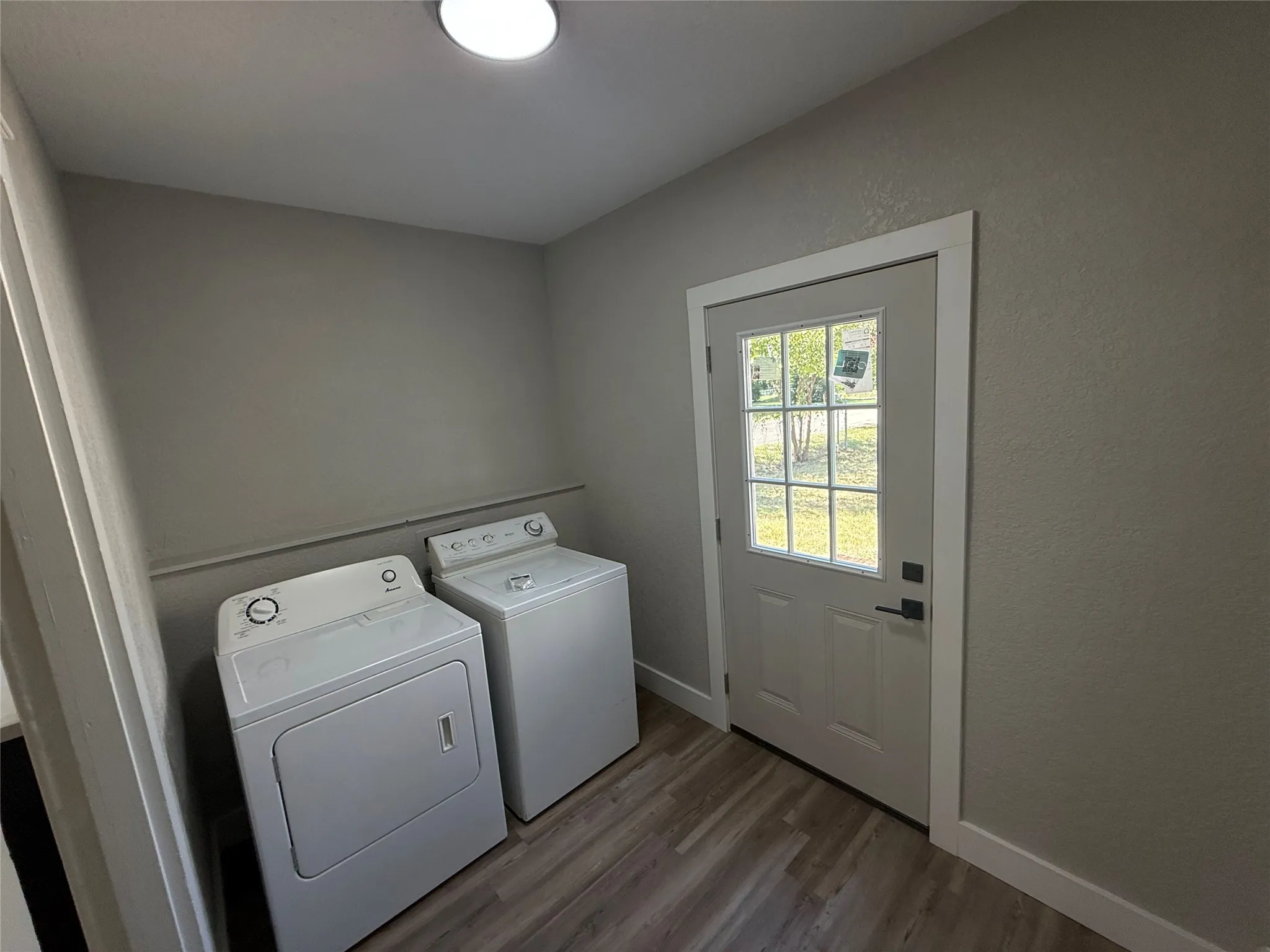 Utility area featuring wood-finish flooring, light gray wall paint, and a white exterior door with glass panes