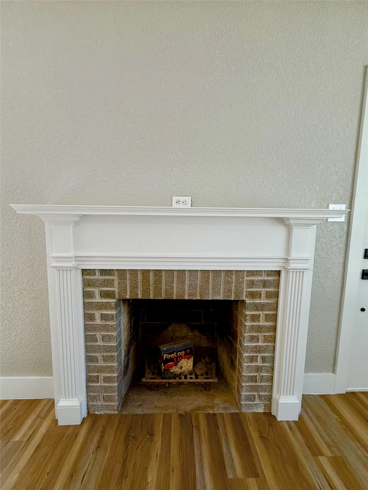 Fireplace featuring a white mantel, fluted columns, and a brick surround