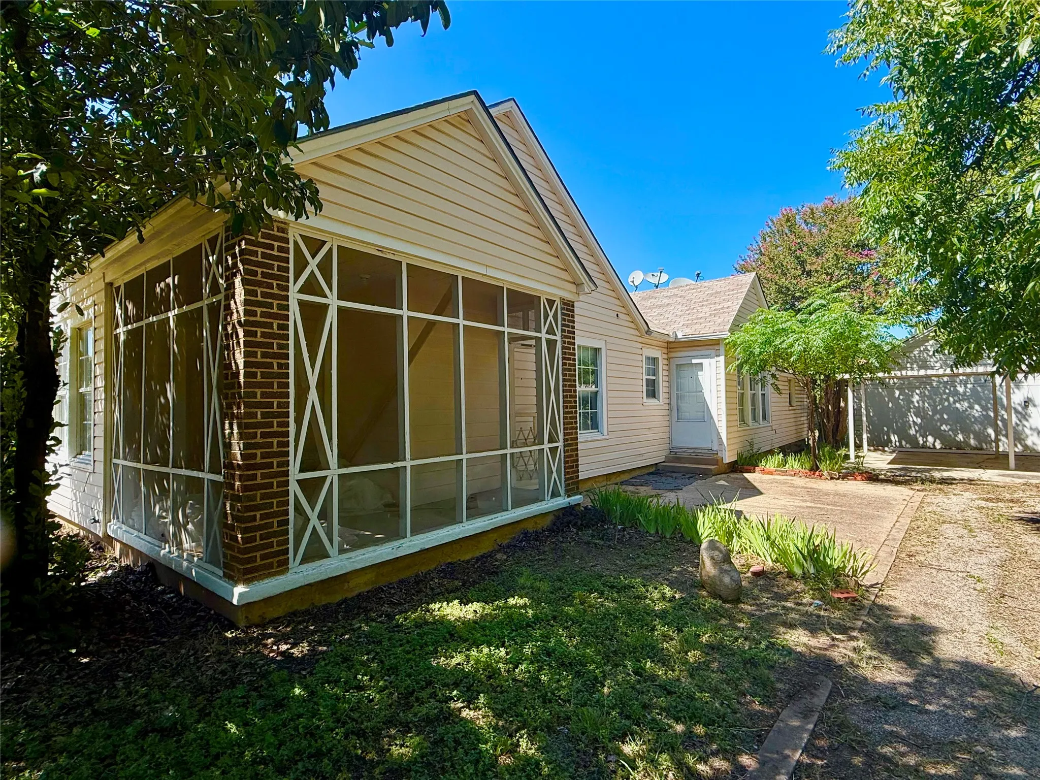 Exterior featuring a screened porch with brick accents, vinyl siding, and a gabled roofline