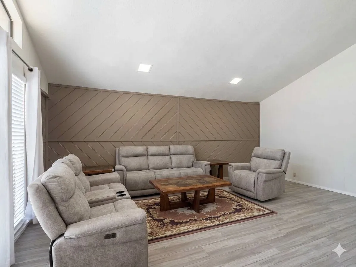 Spacious living area featuring light wood-finish flooring, a textured accent wall, and recessed ceiling lighting