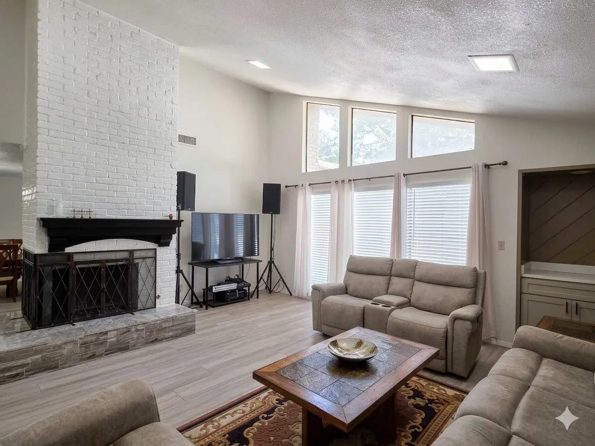 Living area featuring a white brick fireplace with a black mantle, vaulted ceilings, and light wood-finish flooring