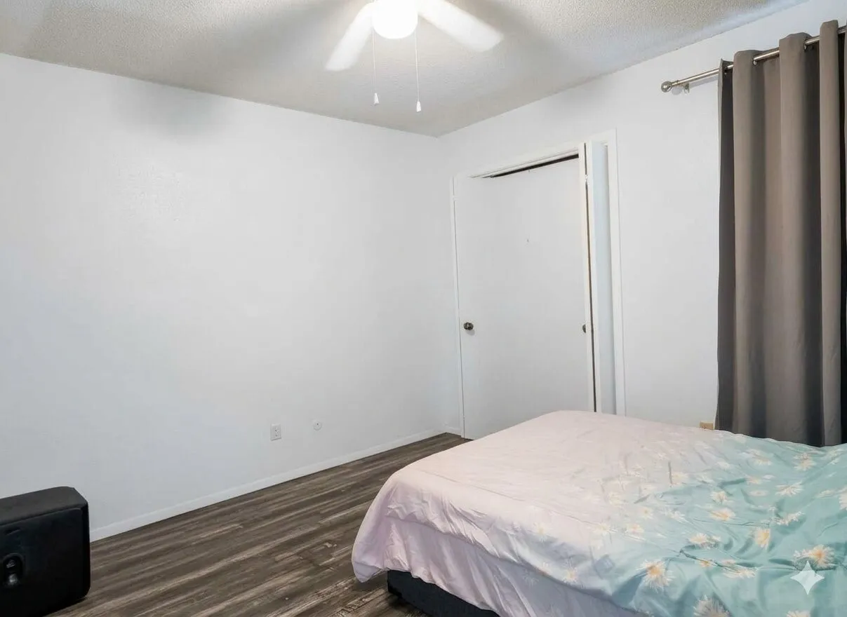 Room featuring wood-finish flooring, white walls, and a ceiling fan