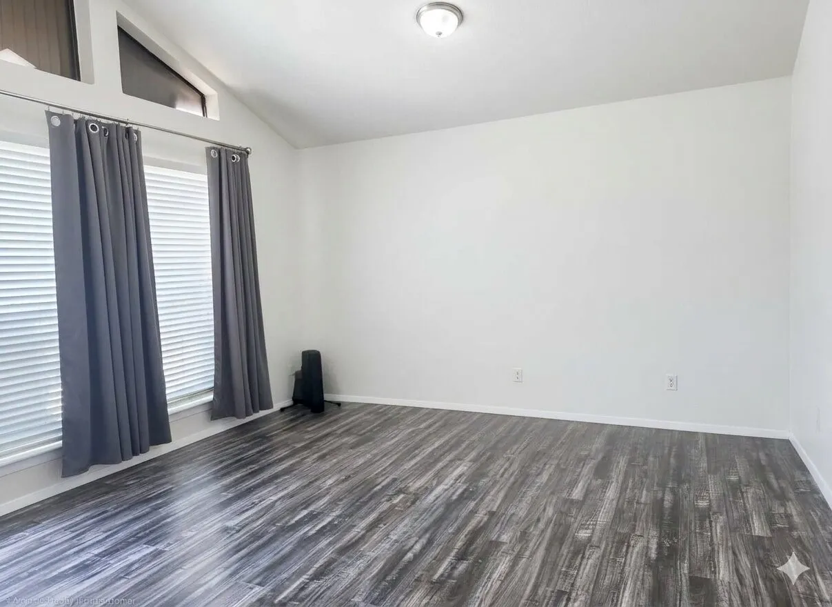 Vaulted ceiling room featuring wood-finish flooring, white walls, and a contemporary flush-mount ceiling light