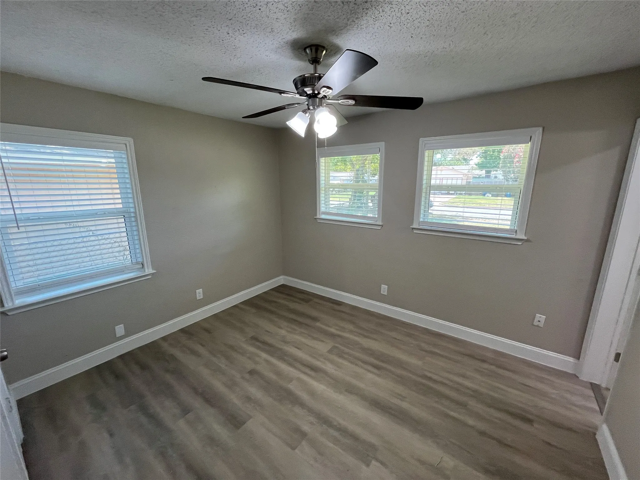Room featuring wood-finish flooring, neutral wall paint, and white baseboards