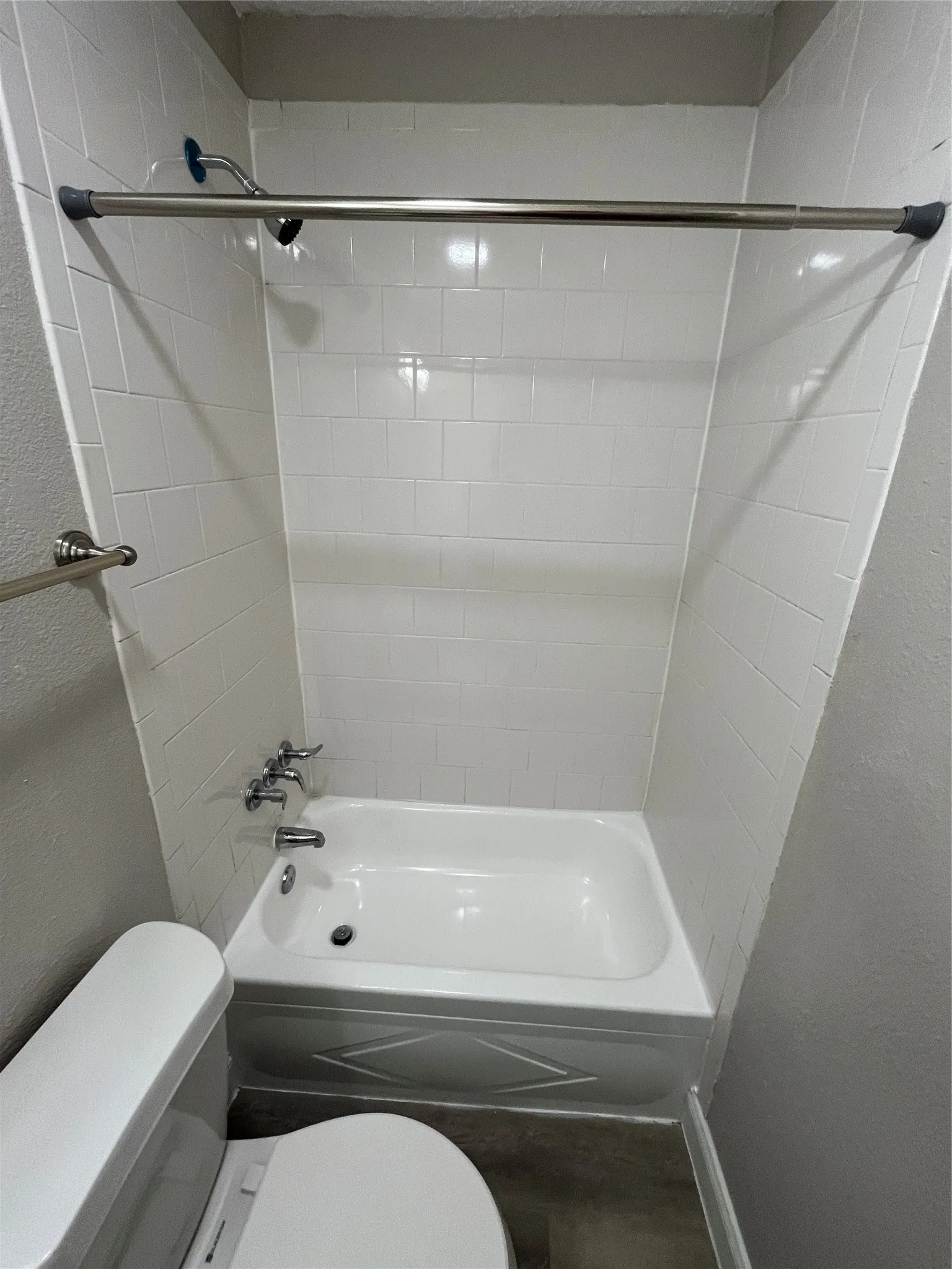 Bathroom featuring a white bathtub, white subway tile surround, and a chrome showerhead