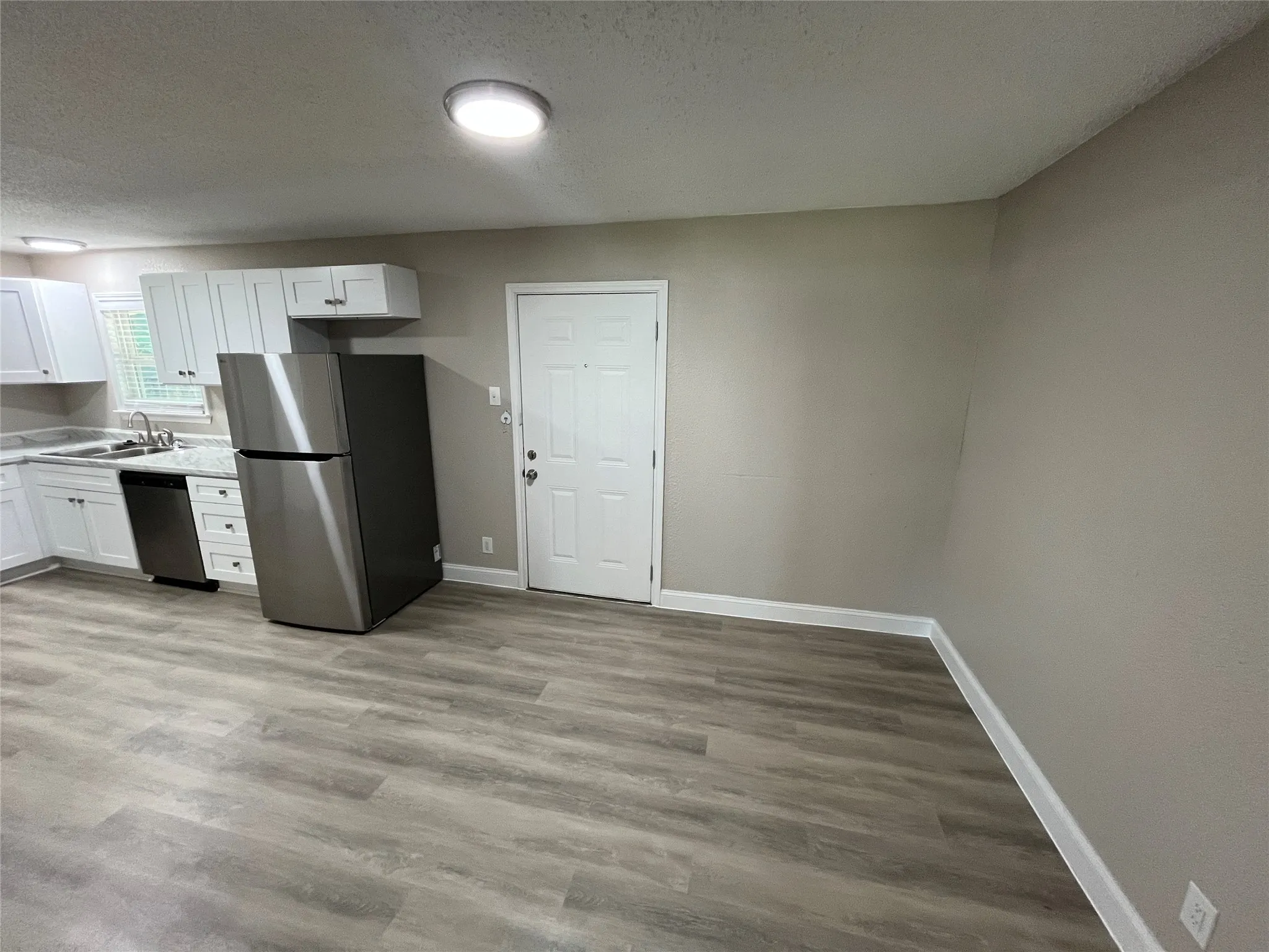Kitchen area featuring white cabinetry, a stainless steel refrigerator, and a stainless steel dishwasher