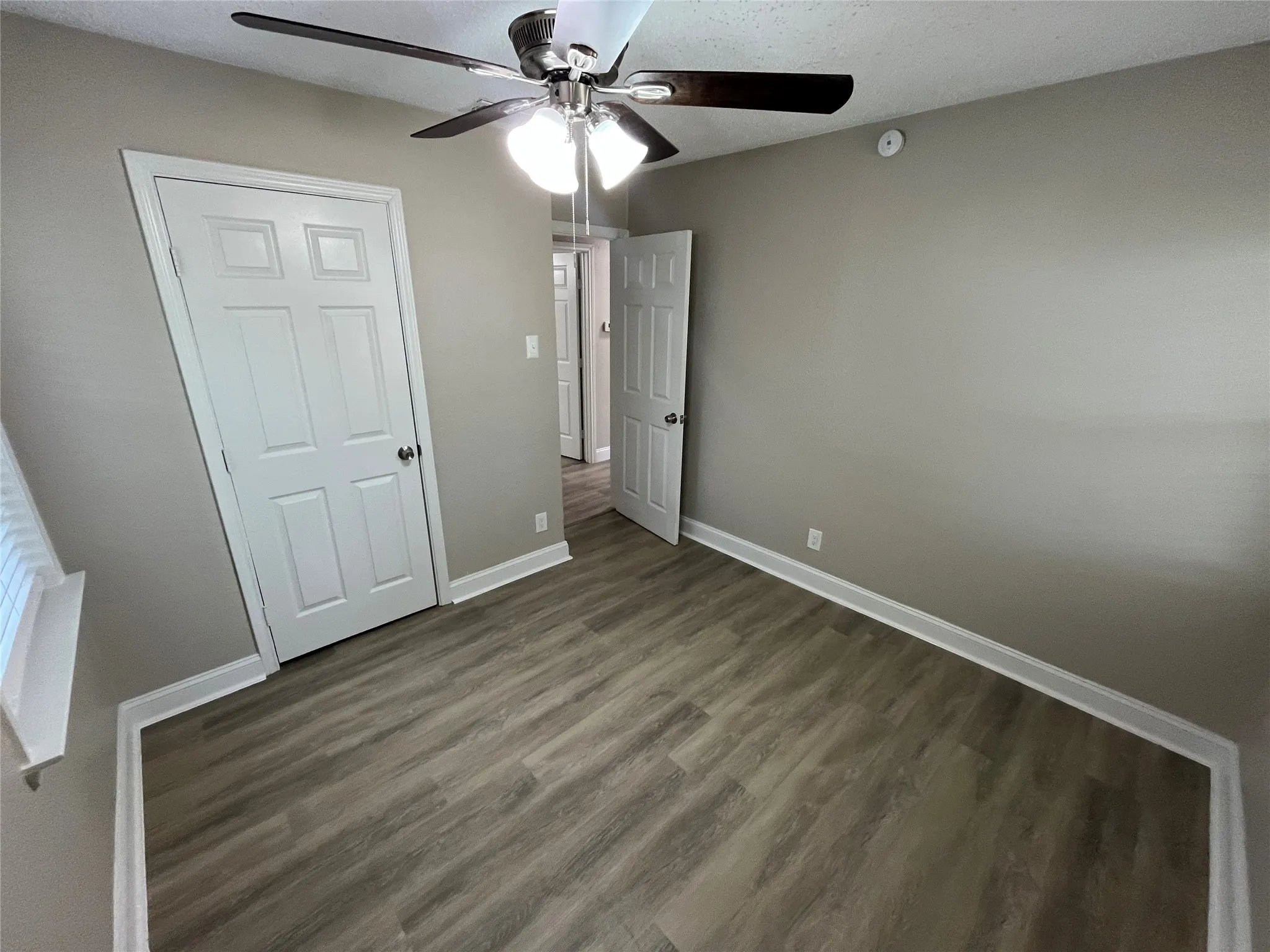 Bedroom featuring wood-finish flooring, neutral wall paint, white trim, and a ceiling fan with integrated lighting
