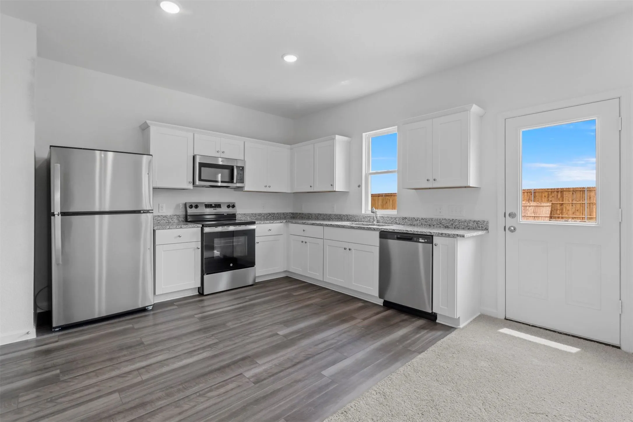 Kitchen featuring white cabinetry, granite countertops, stainless steel appliances, wood-finish flooring, and recessed lighting
