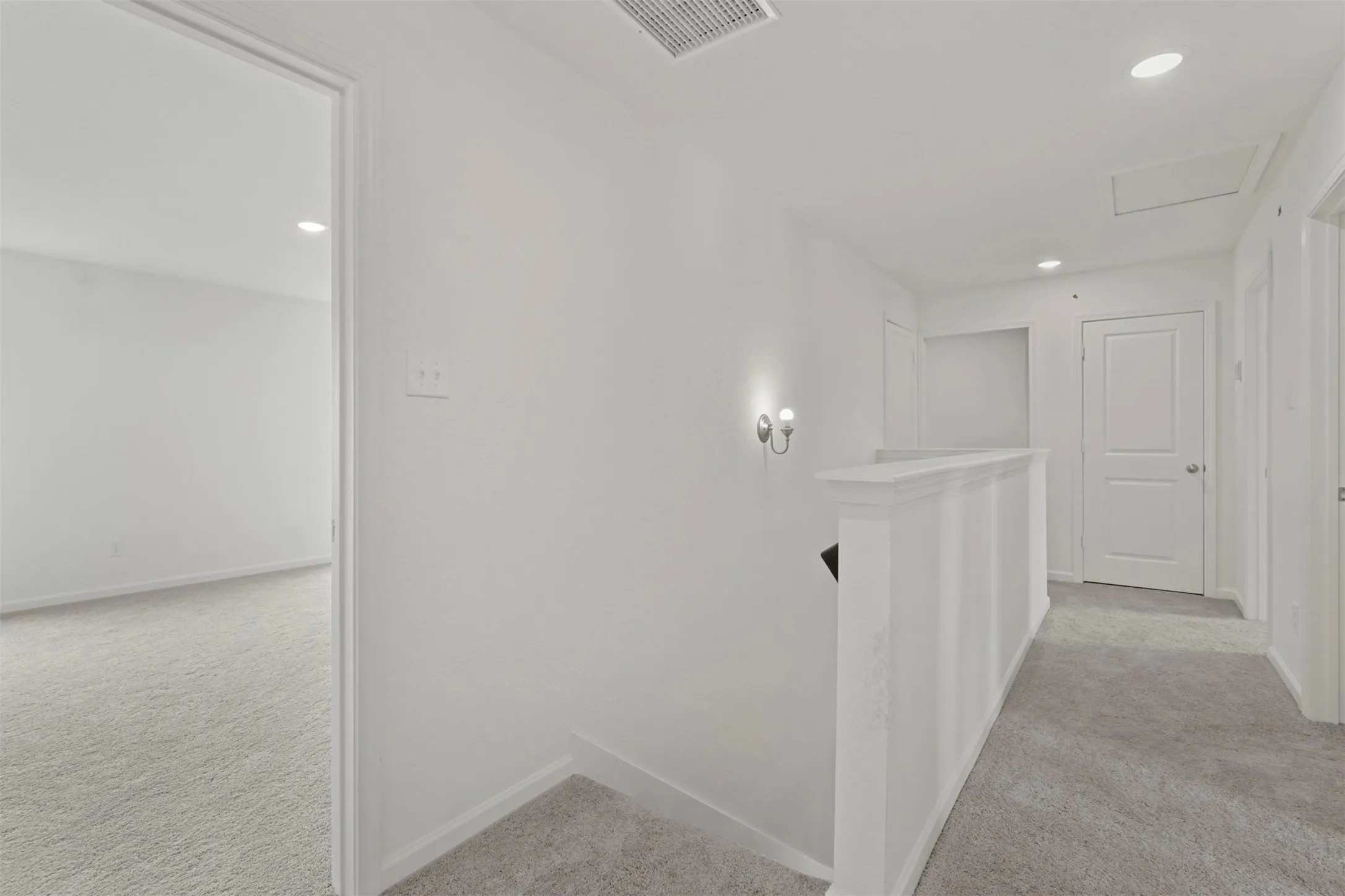 Upper level hallway featuring light gray carpeting, crisp white walls, and recessed lighting