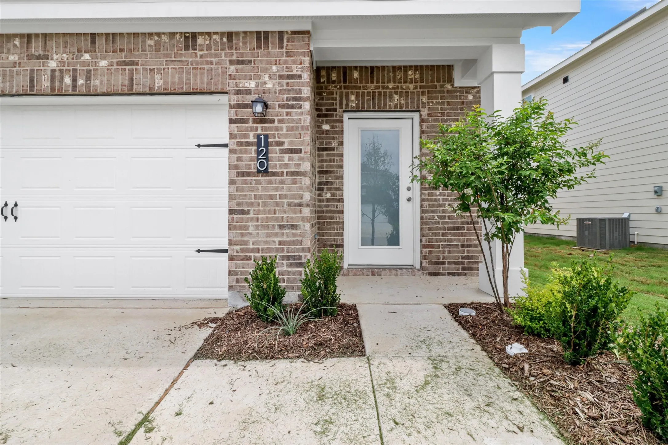 Brick facade entry with a white paneled garage door and decorative hardware