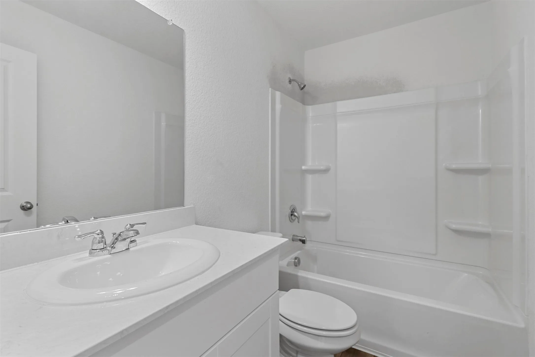 Bathroom featuring a white vanity with a built-in sink, chrome fixtures, and a frameless mirror