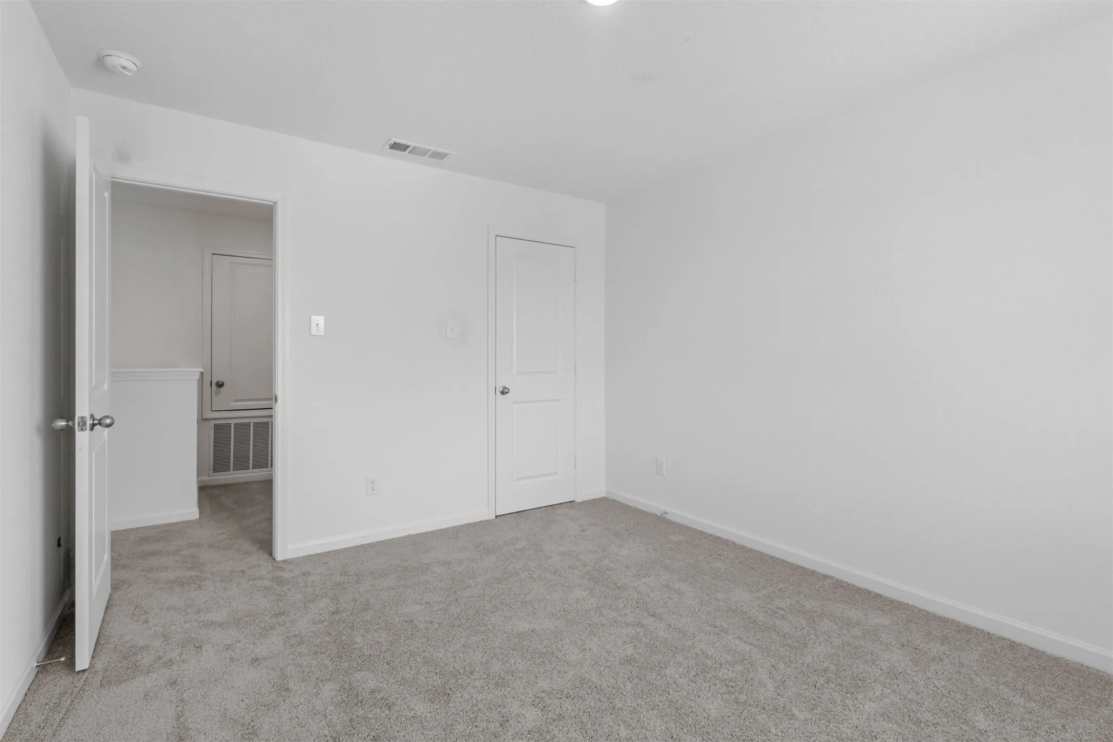 Neutral tone carpeting in a brightly lit room featuring white walls and trim
