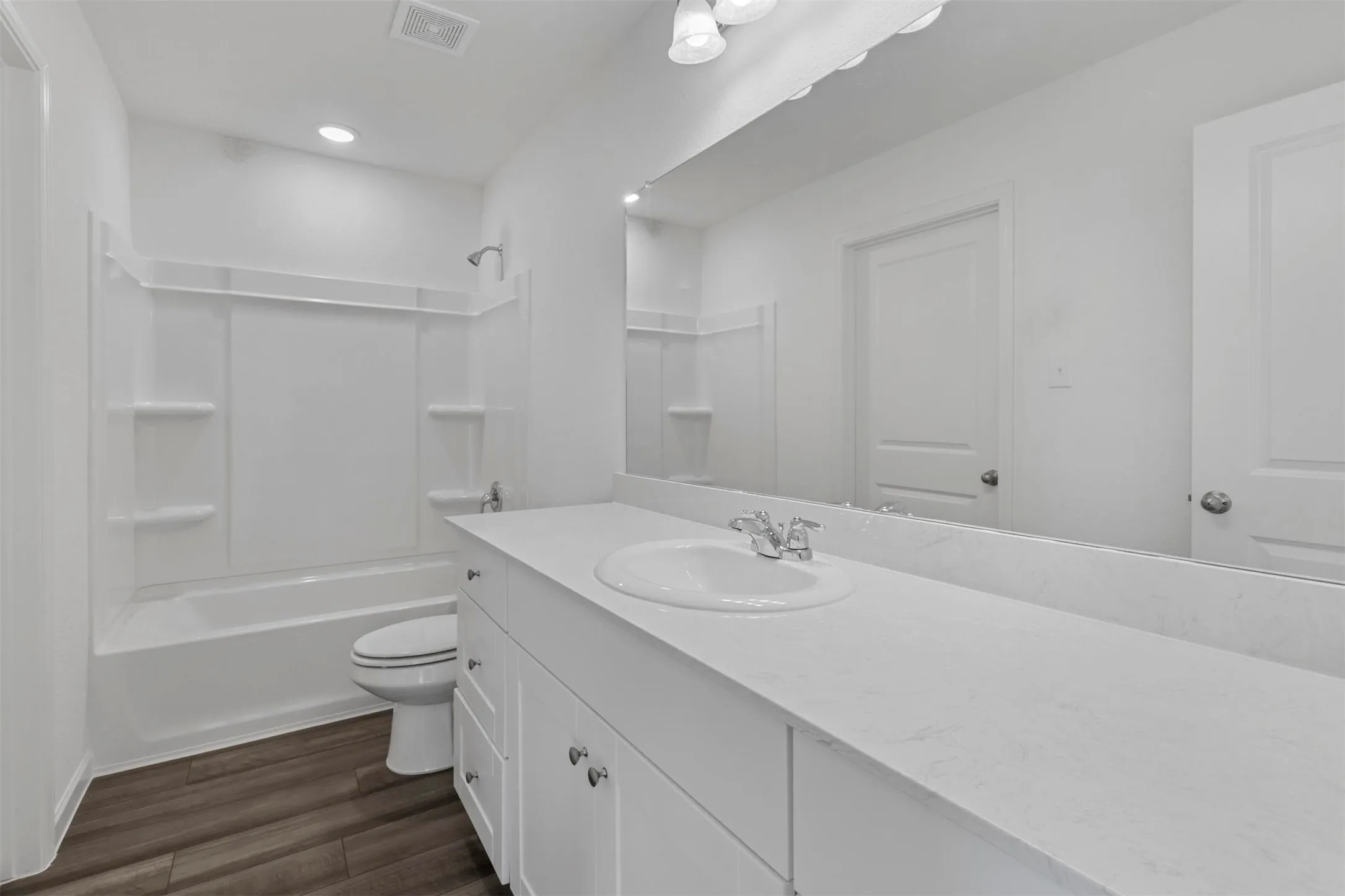 Bathroom featuring a white vanity with an integrated sink, polished chrome faucet, and expansive wall-mounted mirror
