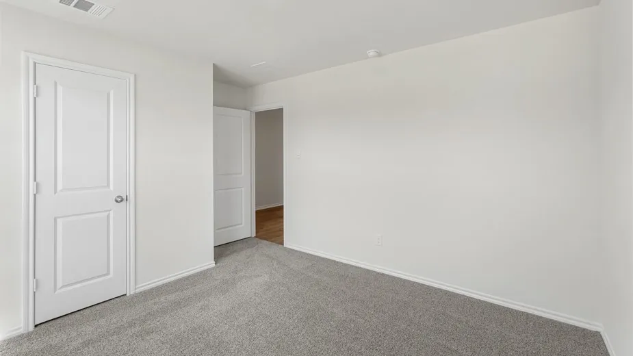 Neutral-toned interior room featuring light gray carpet, white baseboards, and white walls