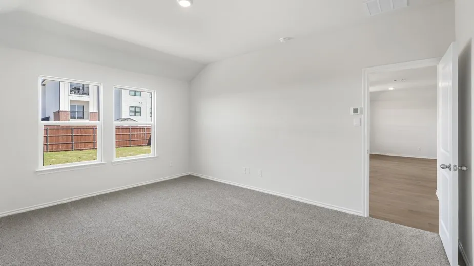 Spacious room featuring gray carpet, white walls, two large windows, recessed lighting, and a white interior door
