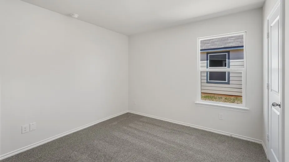 Neutral-toned room featuring a single window, white trim, and gray carpet flooring