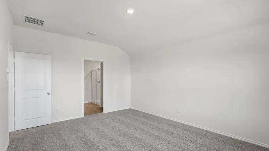 Spacious room featuring vaulted ceilings, light gray carpet, and a white two-panel door