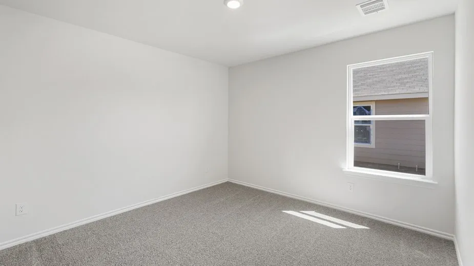 Bright room featuring light gray carpeting, white walls, a single window with white trim, and a recessed ceiling light