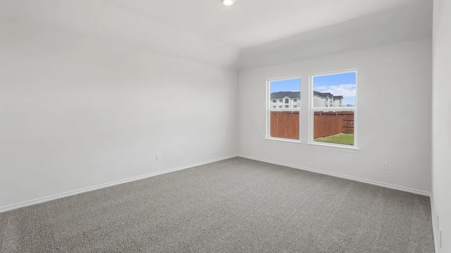 Spacious room featuring light gray carpet, white walls, and a vaulted ceiling with a recessed light fixture
