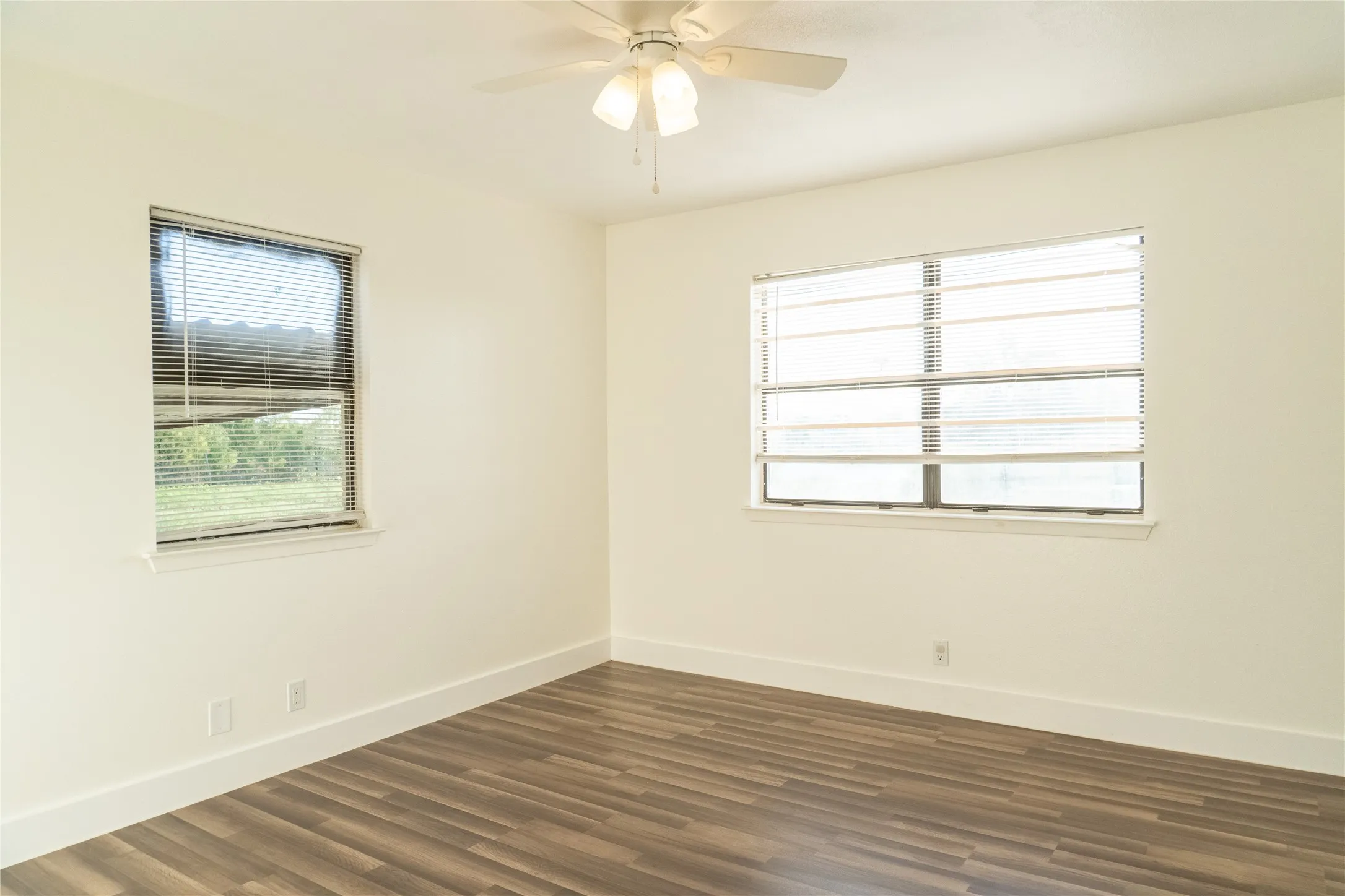 Neutral wall paint with wood-finish flooring and white baseboards