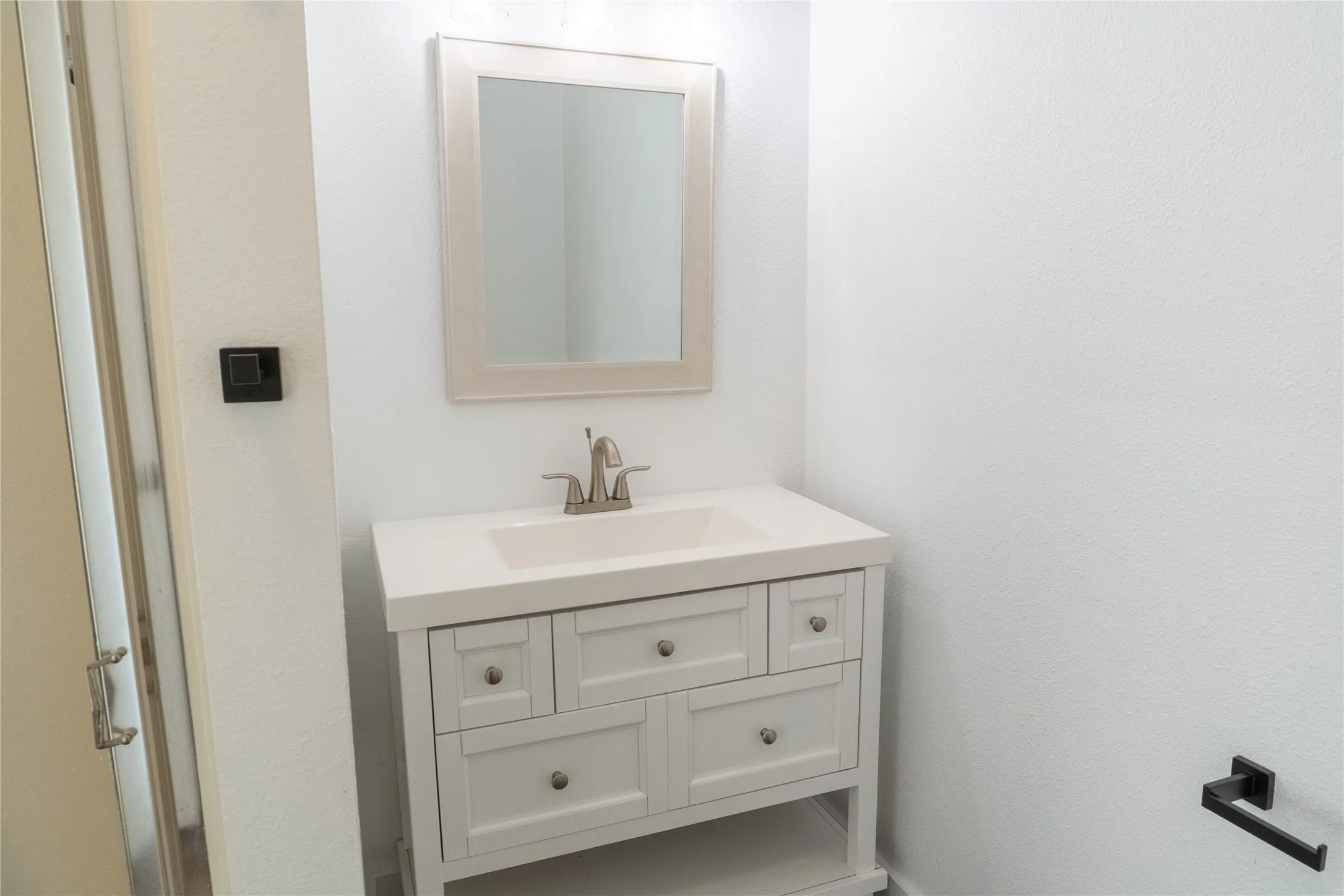 Vanity with integrated sink, light-colored countertop, and brushed nickel faucet