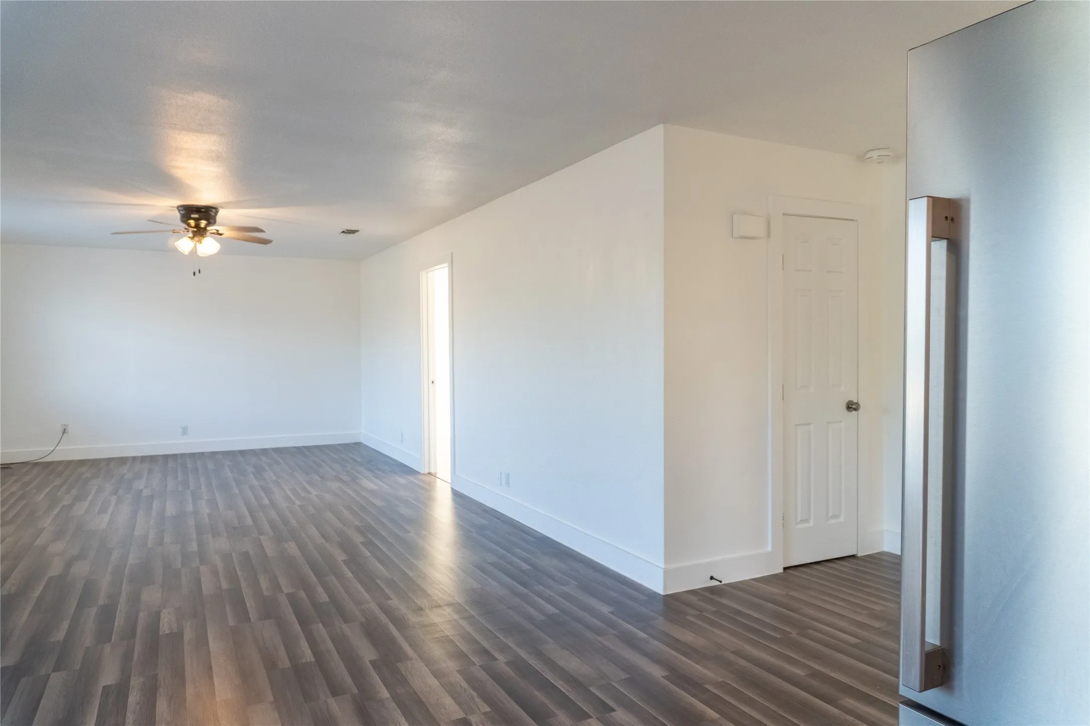 Spacious room featuring wood-finish flooring and a ceiling fan