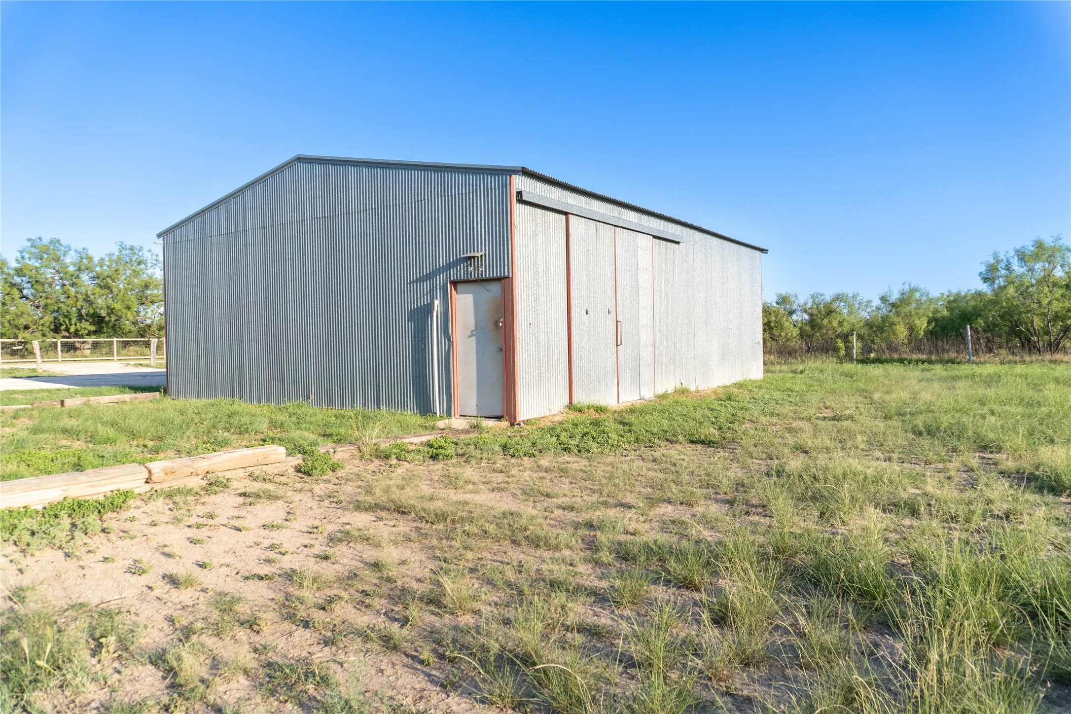 Corrugated metal outbuilding featuring an entry door and sliding barn doors