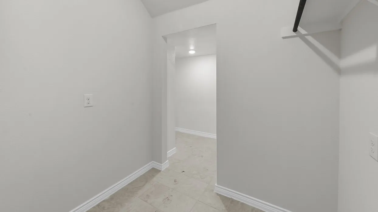 Interior hallway featuring light-toned tile flooring and white baseboards