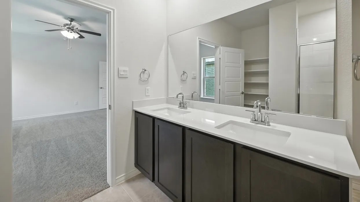 Double vanity with white countertop, chrome fixtures, and dark wood-finish cabinetry