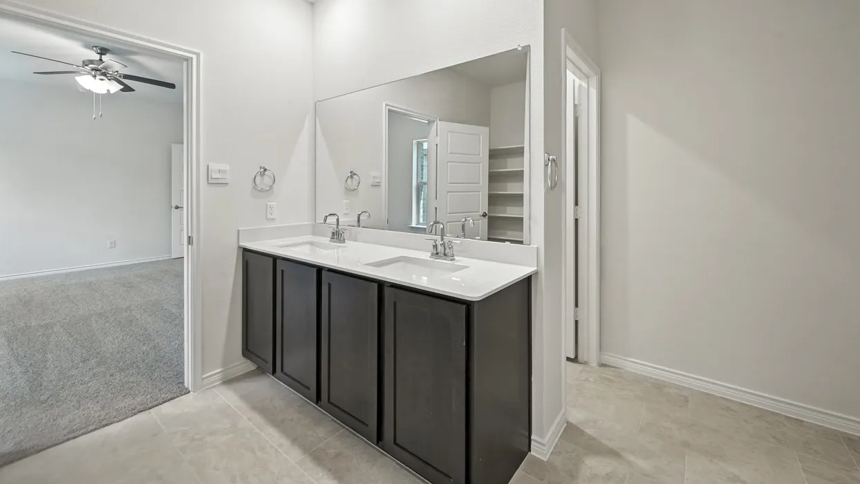 Bathroom featuring a double vanity with dark cabinetry, integrated sinks, and a large mirror