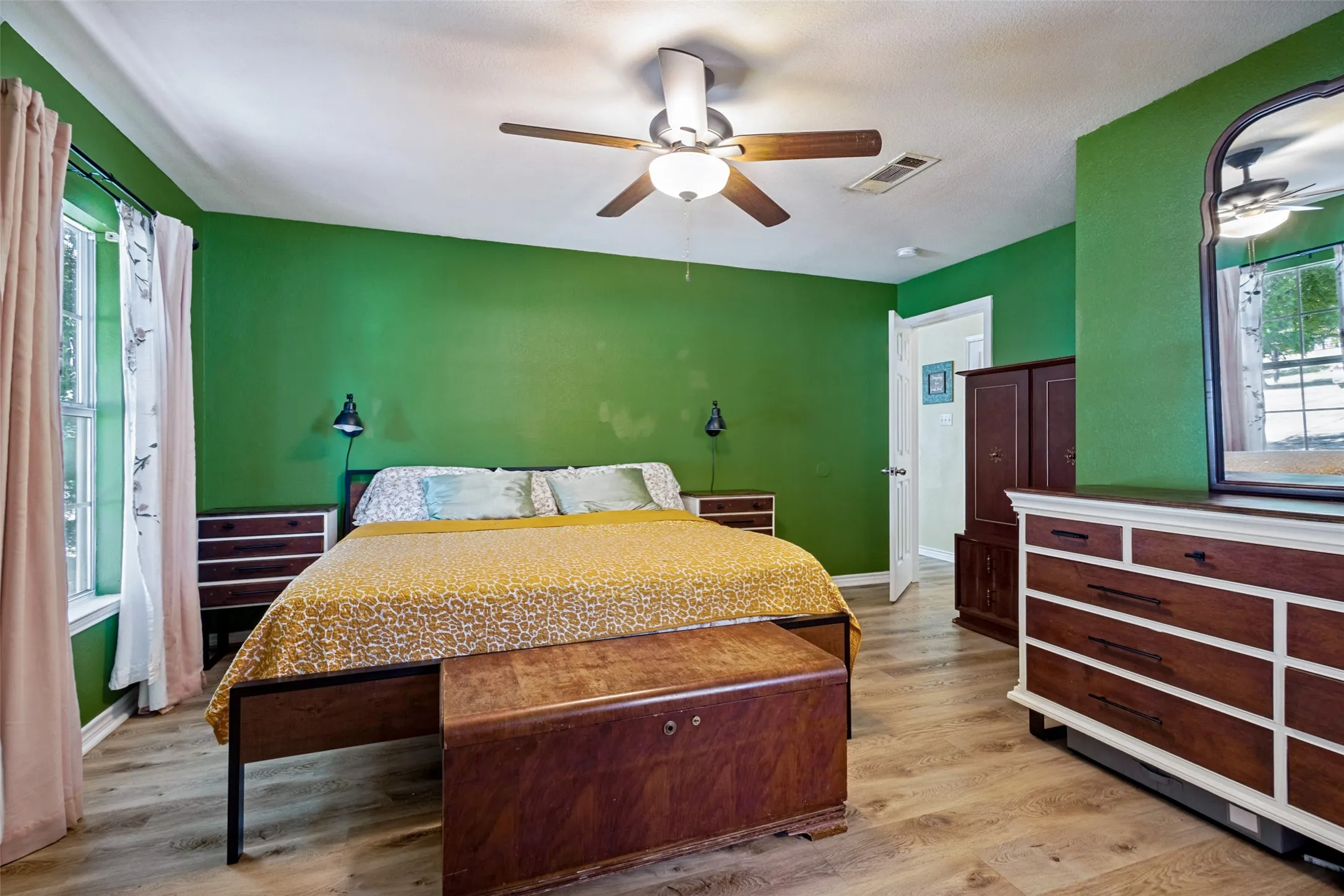The primary bedroom features a large window, ceiling fan, updated flooring, a large walk-in closet and en suite bathroom