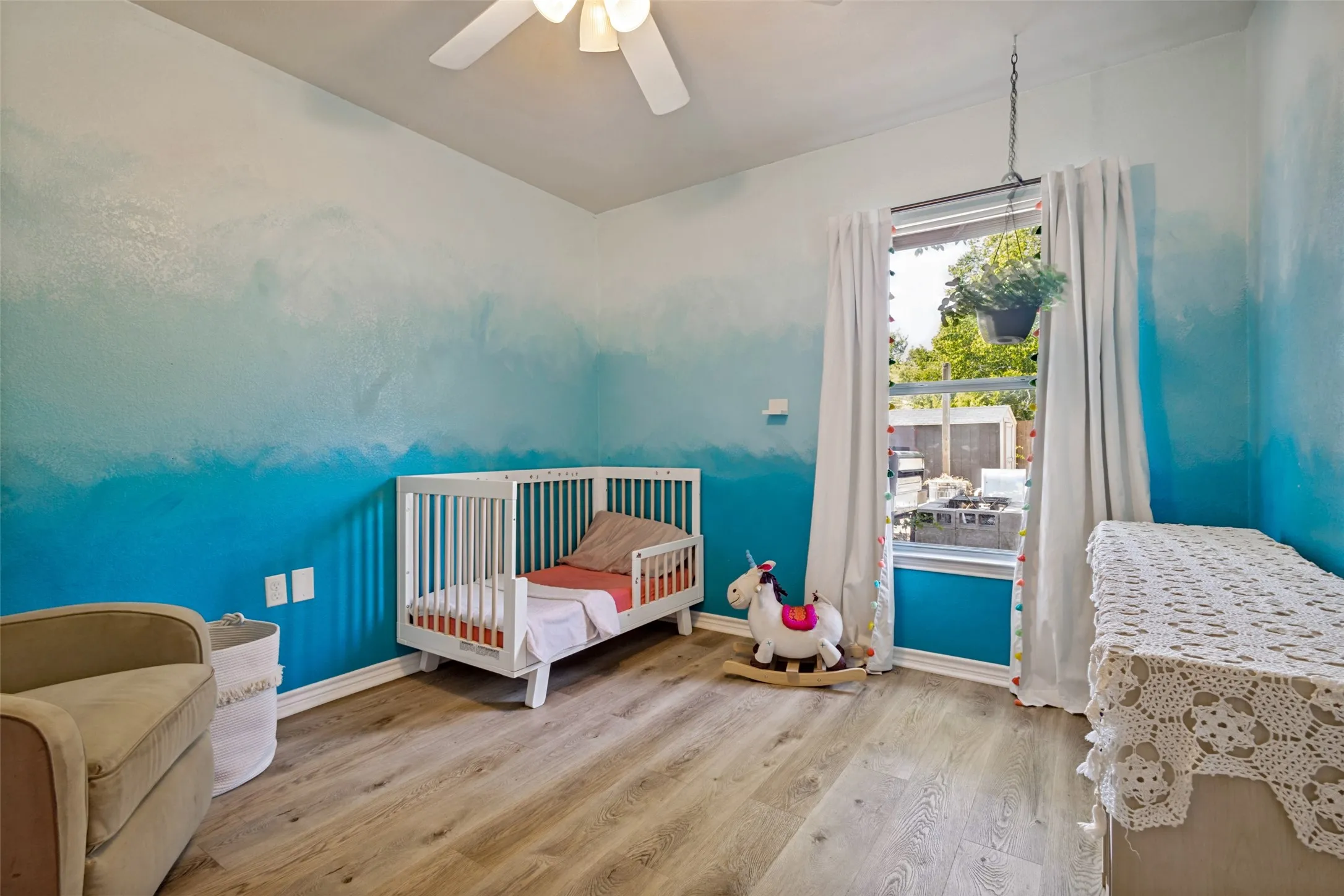 This bedroom features a ceiling fan, updated flooring, and fun cloud and sky motif.
