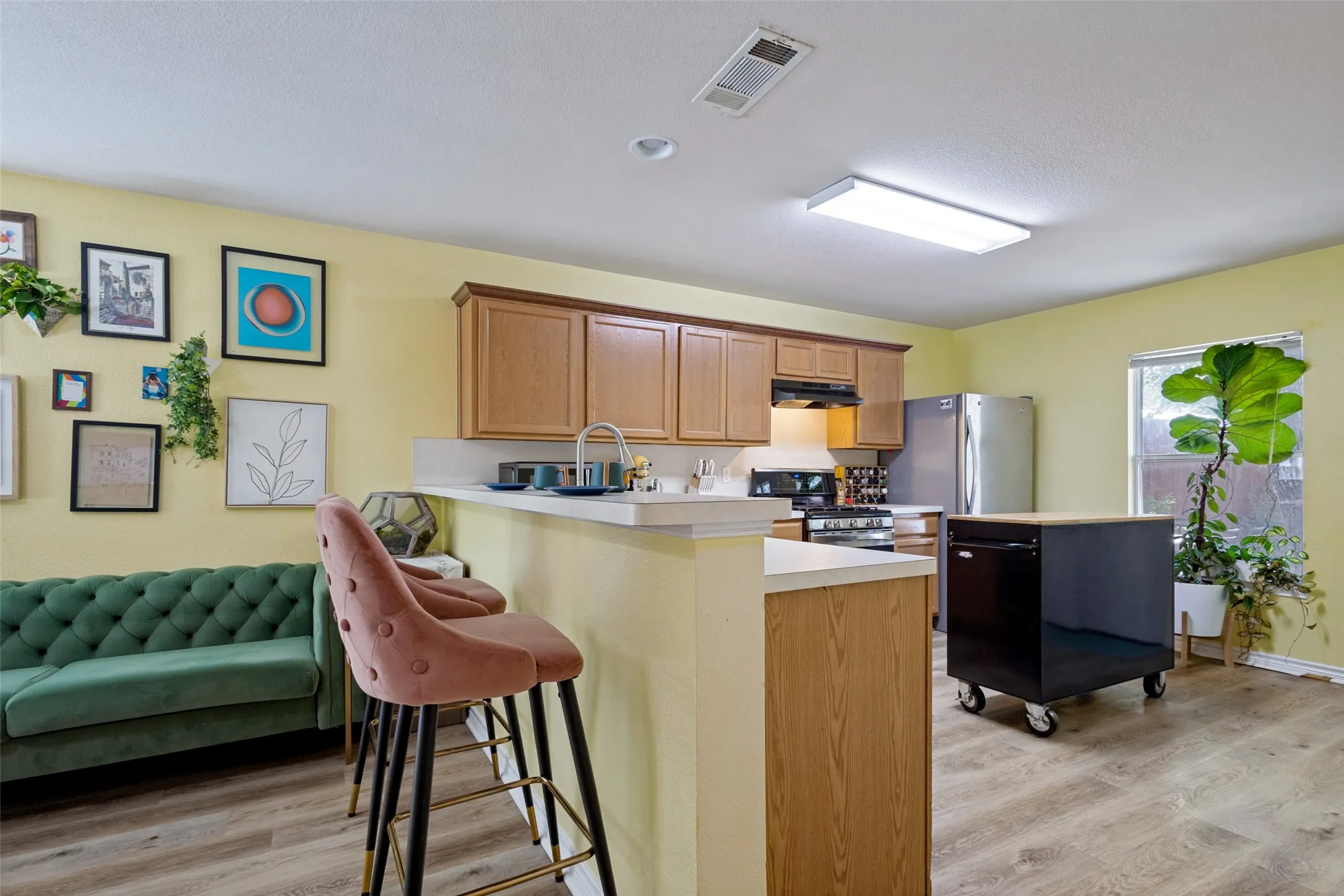 Open concept living and kitchen area featuring a breakfast bar, abundant cabinetry, and natural light.