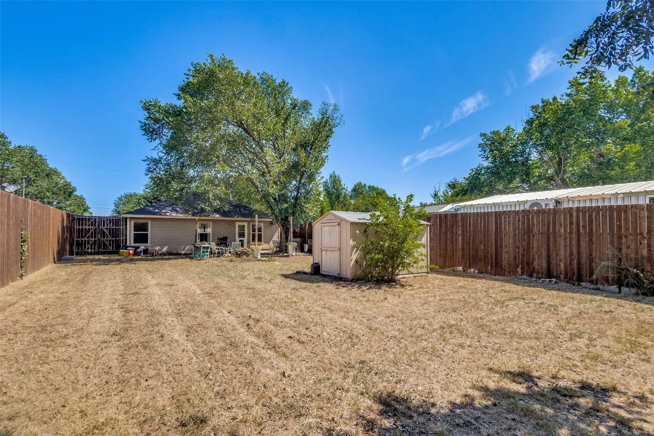 The oversized backyard has a tall privacy fence and storage shed.