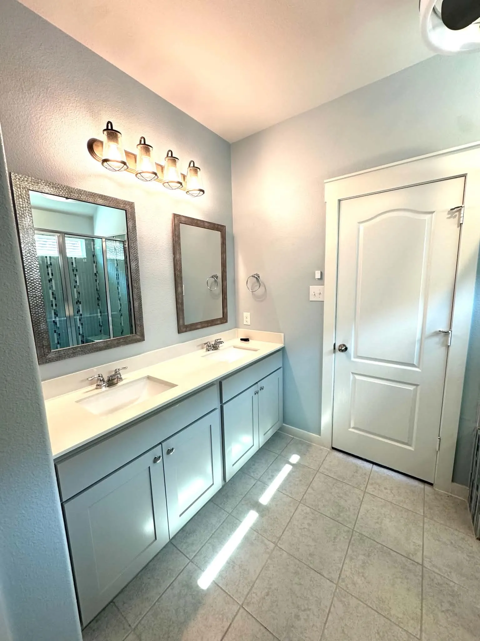 Double vanity with light cabinetry, undermount sinks, and chrome faucets