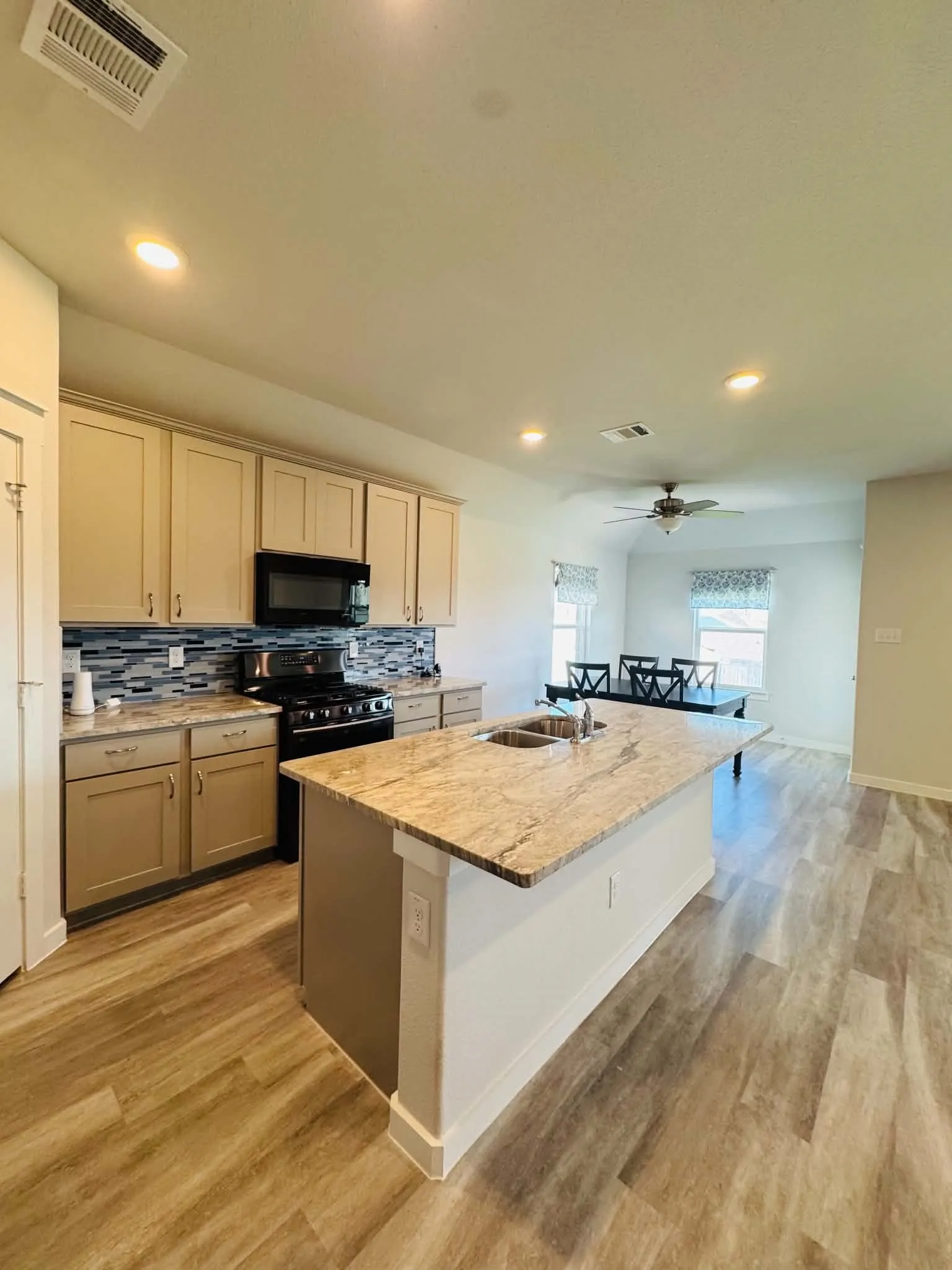 Kitchen featuring a large central island with a built-in sink, stone countertop, and integrated seating