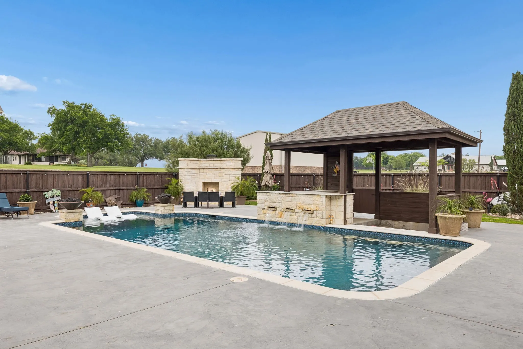The pool has a swim-up bar and was recently converted to a saltwater pool. Note the substantial outdoor fireplace for cozy evenings and added entertainment accent.