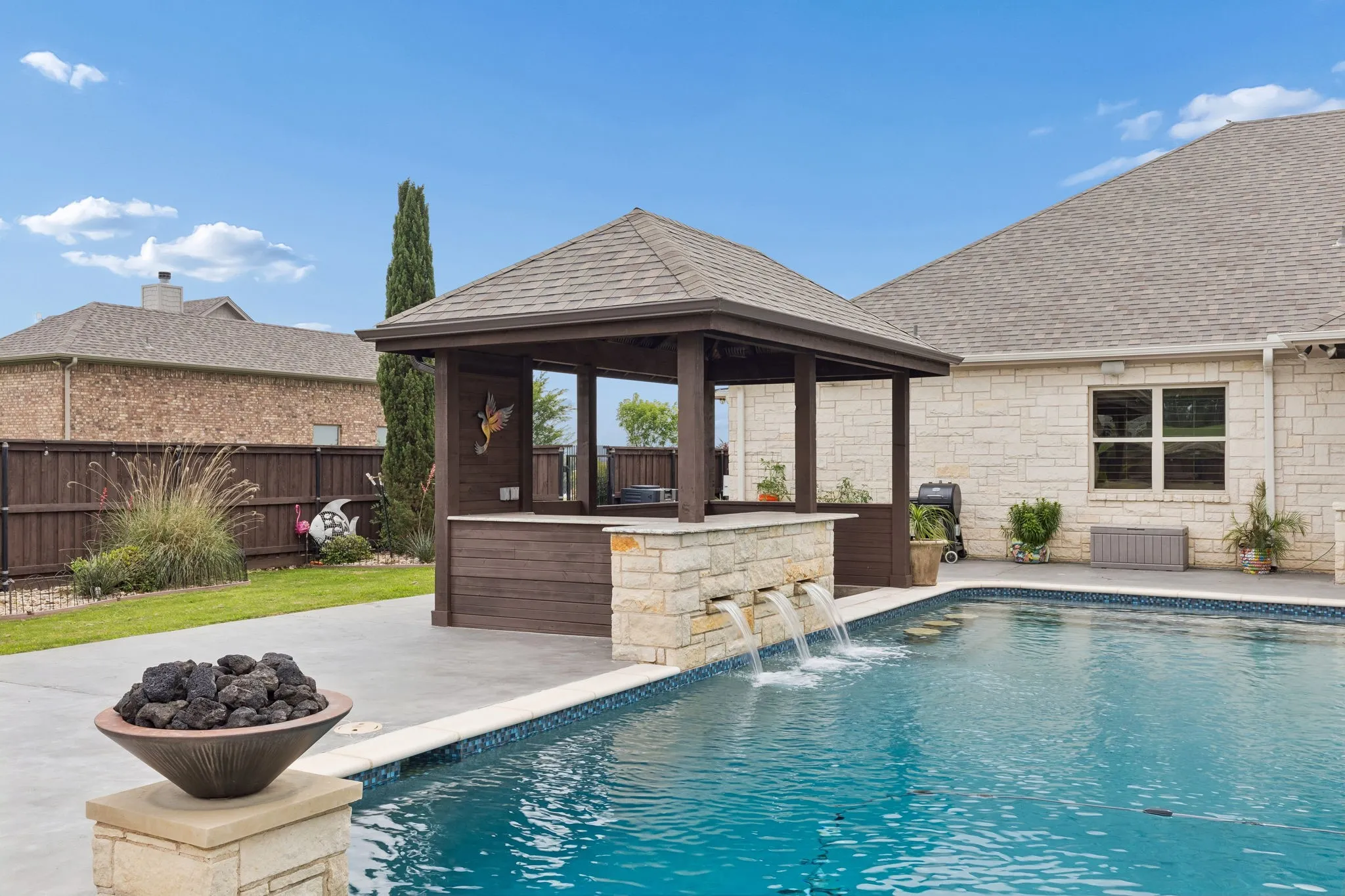 Landscaped flowerbeds and grass flank the pool. Also note the gas flamed urns that accent the pool area.