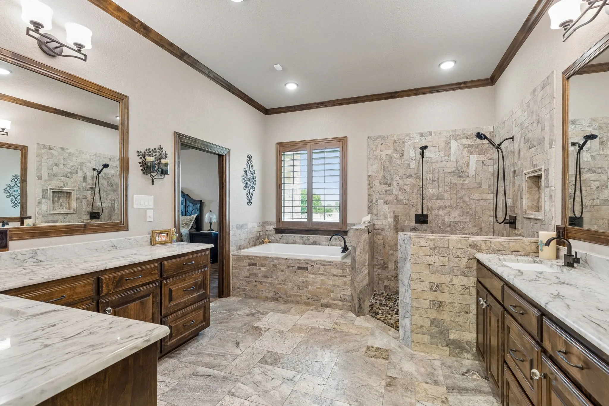 Oversized soaking tub with custom stacked stone accents, dual shower heads, vanities and a dressing area.