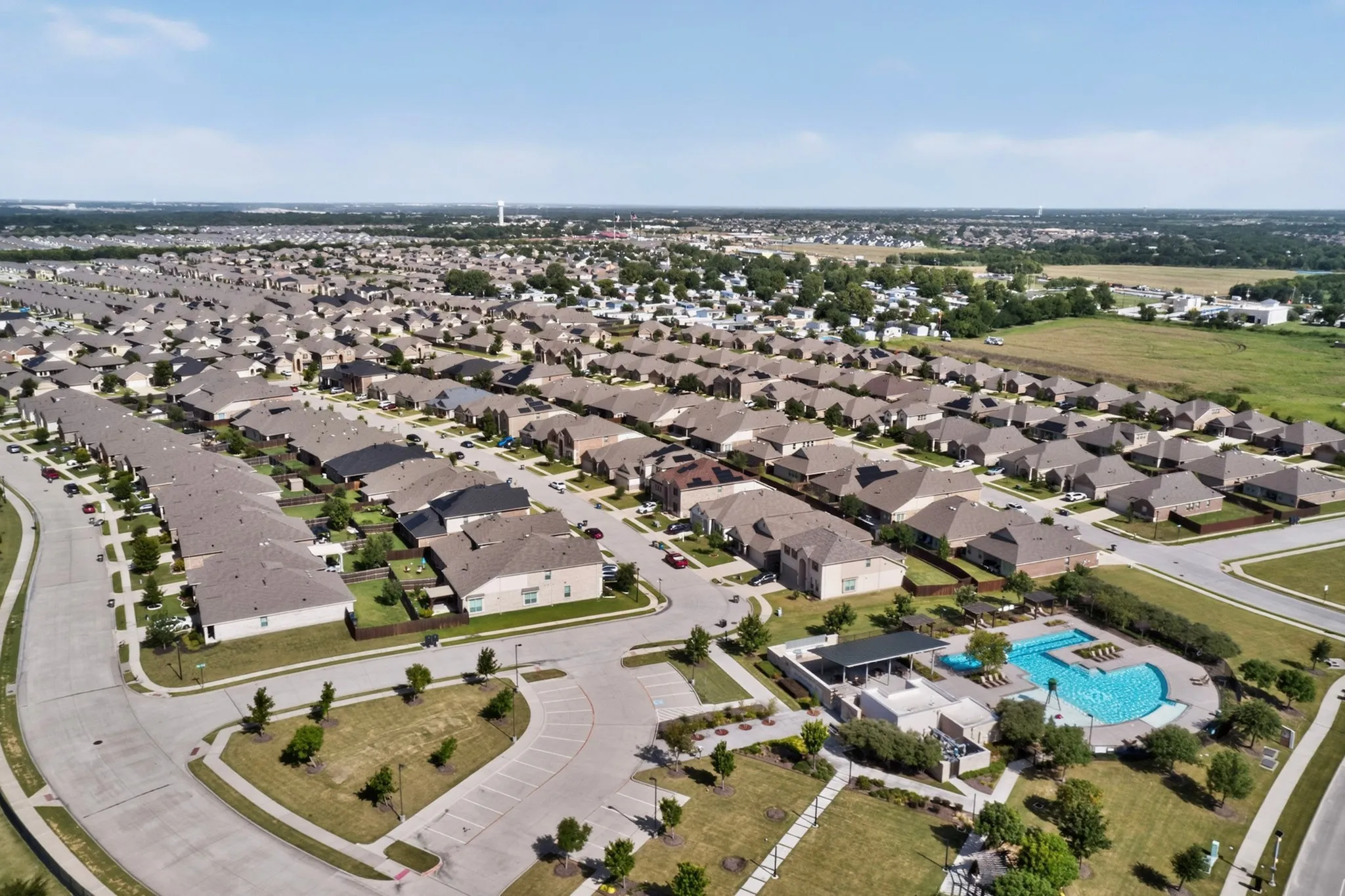 Residential development featuring a community swimming pool, recreational green space, and structured street layouts
