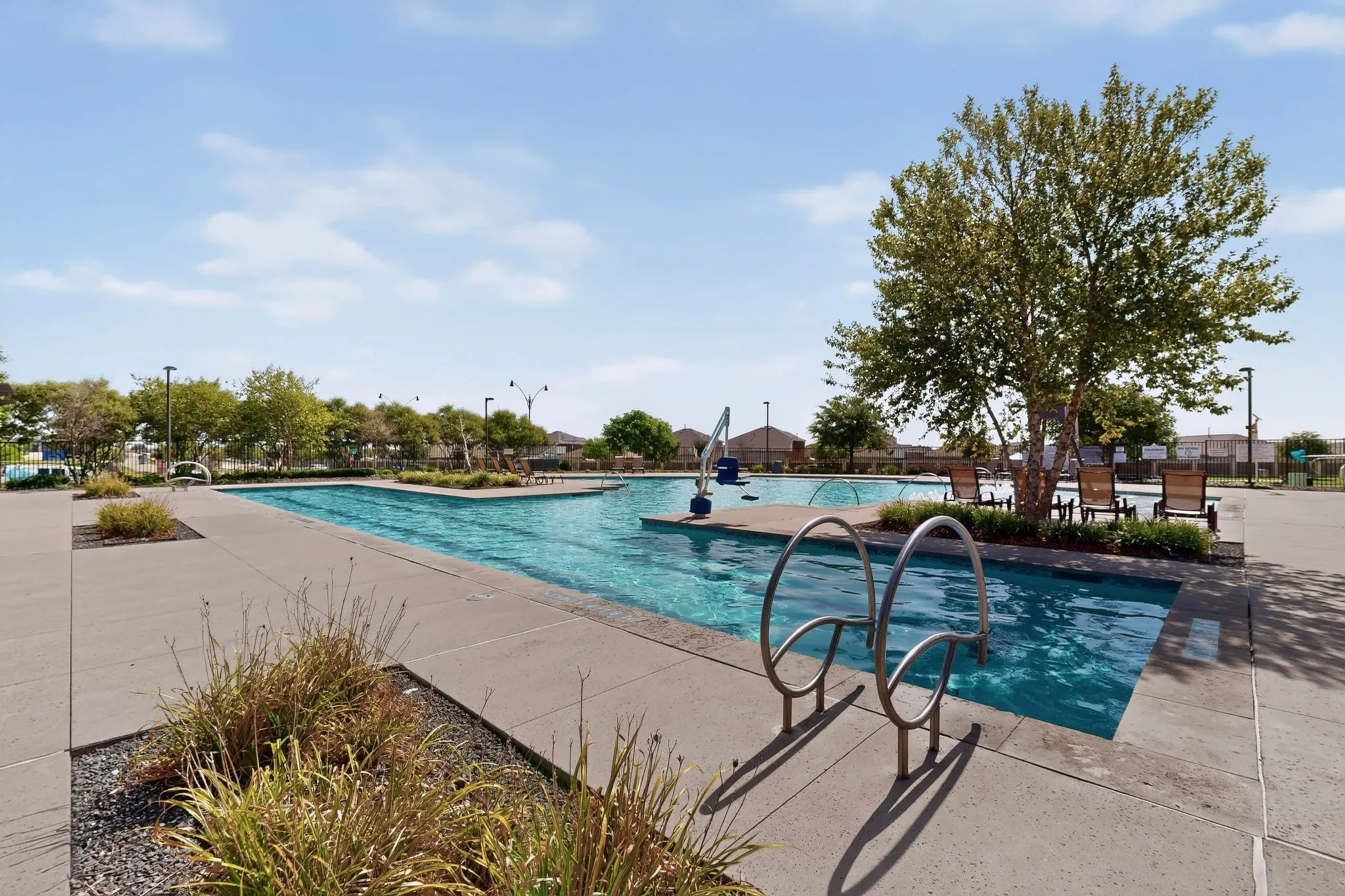 Community swimming pool with concrete decking, lush landscaping, and integrated water features