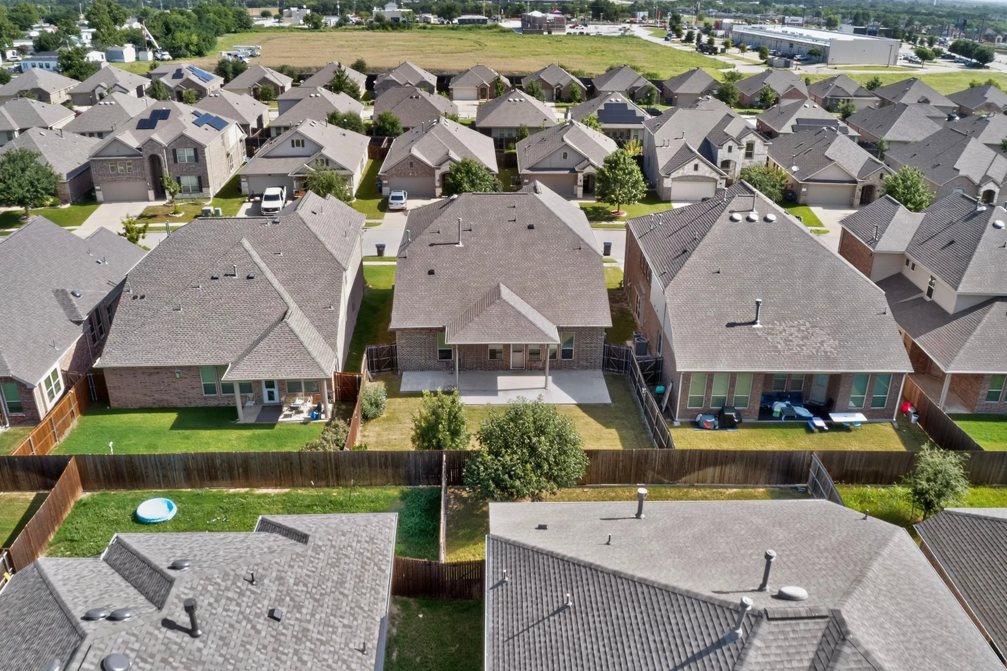 Spacious backyard featuring a covered patio, manicured lawn, and privacy fencing