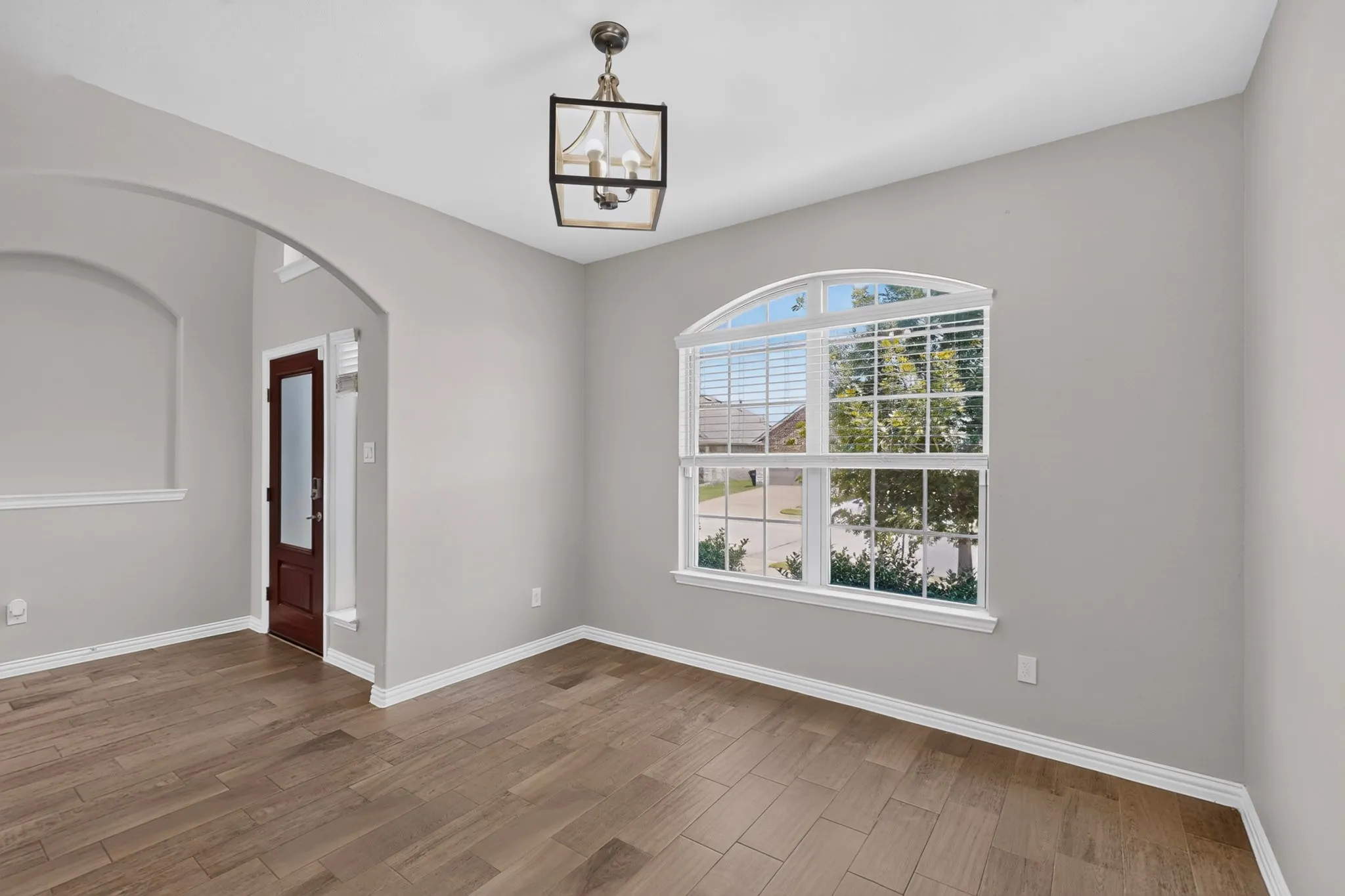 Room featuring wood-finish flooring, light gray walls, and white trim