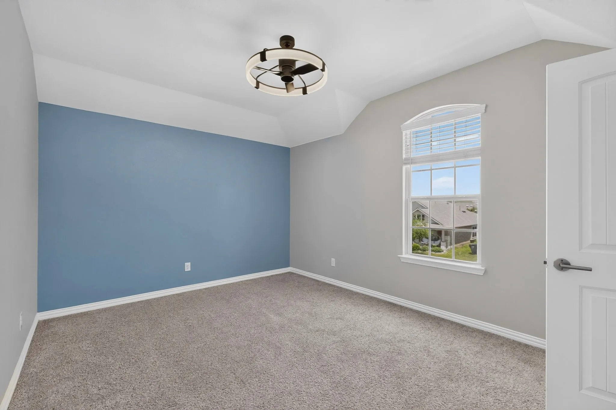 Vaulted ceiling room featuring a decorative ceiling fan, arched window, and plush carpeting