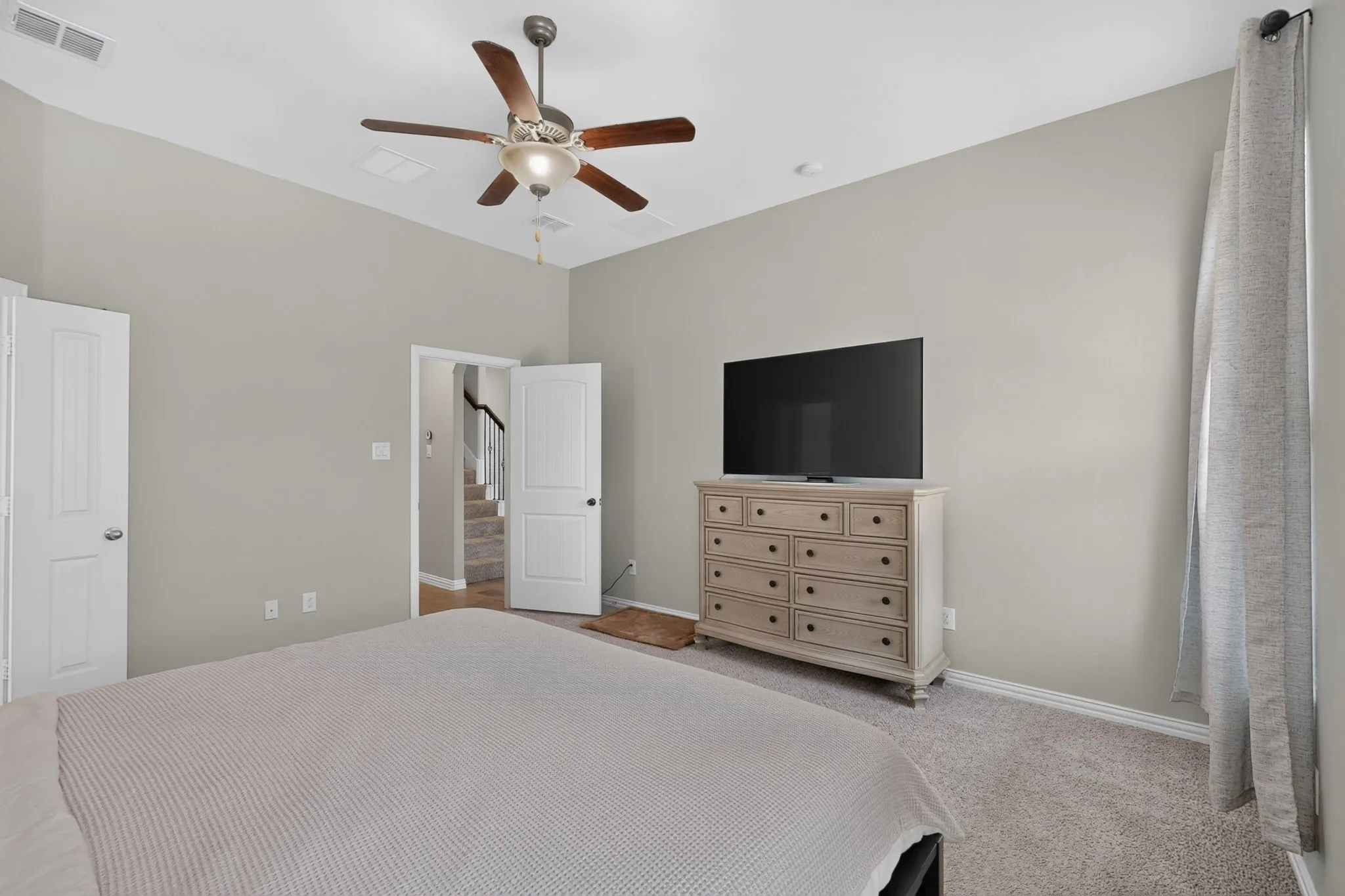 Carpeted room with a vaulted ceiling and ceiling fan