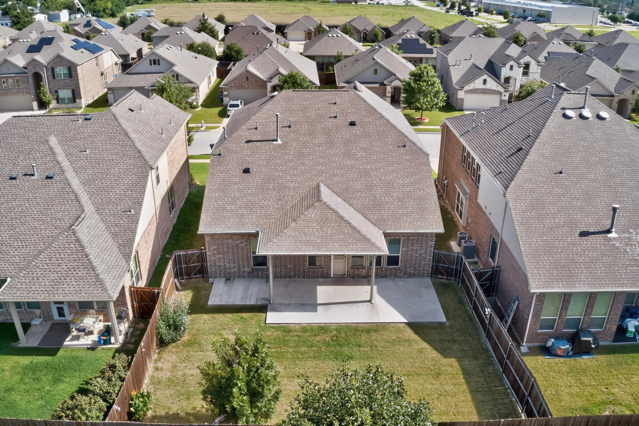 Rear exterior featuring a covered patio, expansive lawn, and mature landscaping