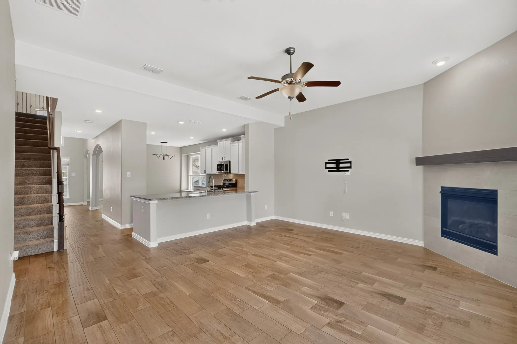 Open-concept living space featuring wood-finish flooring, a contemporary ceiling fan, and recessed lighting